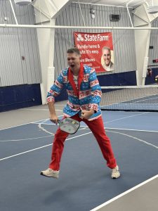 Man playing pickleball in a blue Christmas suit with red pants